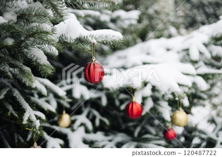 Happy New Year Christmas tree decorates with yellow red glass ball on branch snow outdoors for family winter holiday. Festival mood  120487722