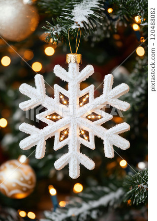 Decorative snowflake ornament hanging on a Christmas tree with lights. 120488082