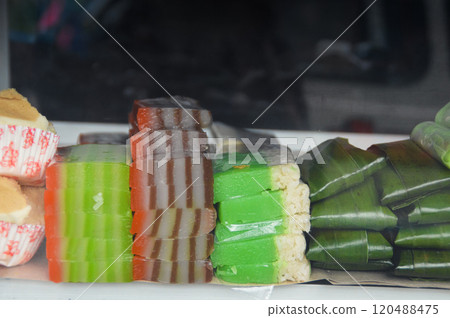 Colorful kue lapis and seri muka that are steamed glutinous rice cake among other traditional Indonesian sweets that are behind a glass display. Authentic local cuisine of Indonesia Colorful kue lapis and seri muka that are steamed glutinous rice cake among other traditional Indonesian sweets that are behind a glass display. Authentic local cuisine of Indonesia 120488475