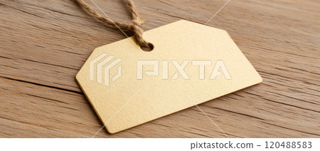 Blank golden price tag on wooden surface with subtle texture background. Blank golden price tag on wooden surface with subtle texture background. 120488583