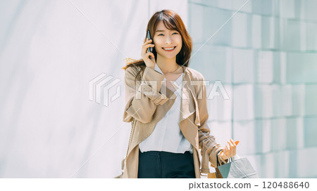 微笑的女士一邊用智慧型手機聊天一邊購物 微笑的女士一邊用智慧型手機聊天一邊購物 120488640