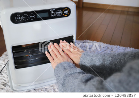 Warming your hands with a fan heater 120488857