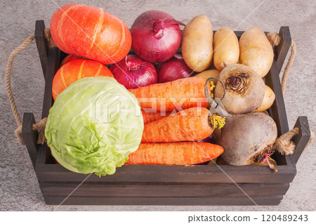 Vegetables in a wooden box on a concrete background. Cabbage, carrots, onions, pumpkins and beets. 120489243
