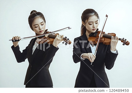 Two young women violinists playing violins wearing formal suits Two young women violinists playing violins wearing formal suits 120489450