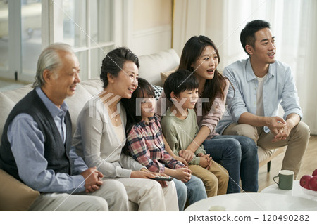 three generation asian family watching tv together at home three generation asian family watching tv together at home 120490282