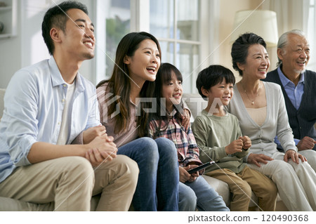 three generation asian family watching tv together at home three generation asian family watching tv together at home 120490368