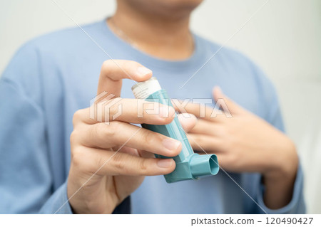 Asthma and chronic obstructive pulmonary disease COPD, Asian young man using metered dose inhaler MDI. Asthma and chronic obstructive pulmonary disease COPD, Asian young man using metered dose inhaler MDI. 120490427