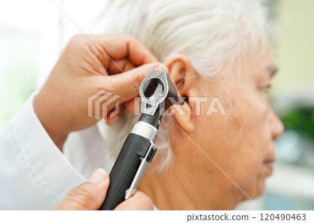 Otolaryngologist or ENT physician doctor examining senior patient ear with otoscope, hearing loss problem. Otolaryngologist or ENT physician doctor examining senior patient ear with otoscope, hearing loss problem. 120490463