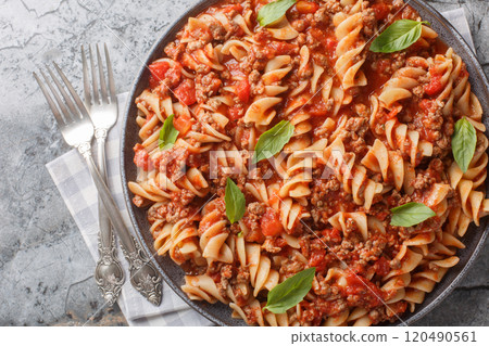 Italian Fusilloni Pasta with ground meat, tomato sauce and vegetables closeup on the plate. Horizontal top view Italian Fusilloni Pasta with ground meat, tomato sauce and vegetables closeup on the plate. Horizontal top view 120490561