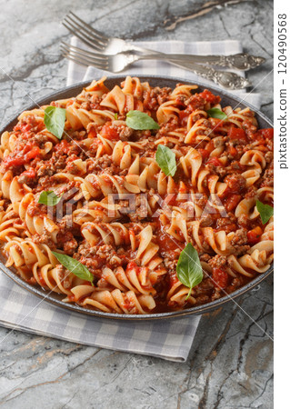 Italian Big Fusilloni bolognese pasta with a beef tomato sauce closeup on the plate. Vertical 120490568