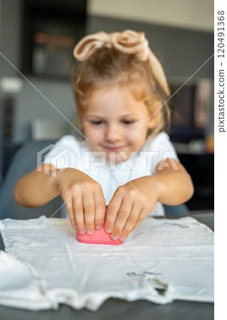 Little girl with a stamp with a name for signing children's things. Identification of personal clothing. Focus on stamp 120491368