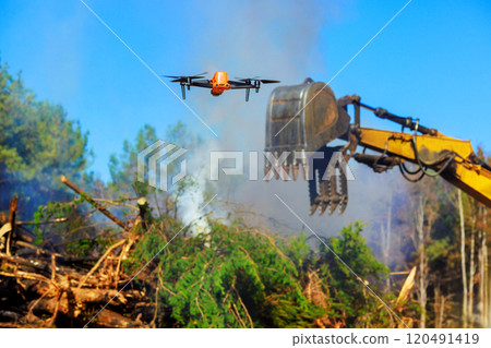 Inspector uses drone to monitor burning of trees as part of land clearing process. 120491419