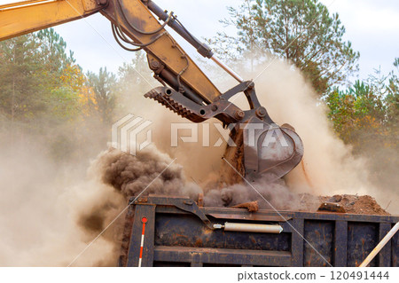 An excavator is to process move earth into dump truck at construction site An excavator is to process move earth into dump truck at construction site 120491444