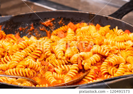 Rich and flavorful fusilli pasta with a vibrant tomato sauce, perfect for a warm, satisfying meal. 120491573
