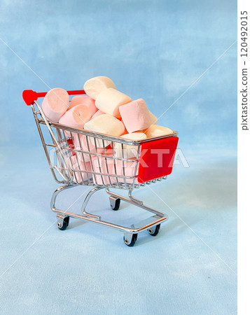 Miniature cart from a supermarket with marshmallows. Blue background Miniature cart from a supermarket with marshmallows. Blue background 120492015