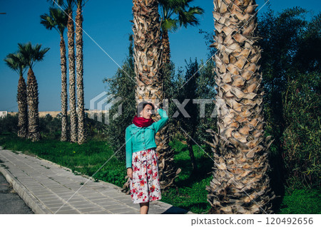 young woman in bright clothes stands in front of palm trees young woman in bright clothes stands in front of palm trees 120492656