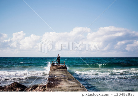a portrait of a young man on a pier, waves splashing and crashing against the pier a portrait of a young man on a pier, waves splashing and crashing against the pier 120492953