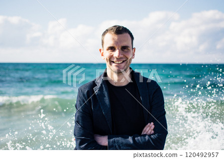 a portrait of a young man on a pier, waves splashing and crashing against the pier 120492957