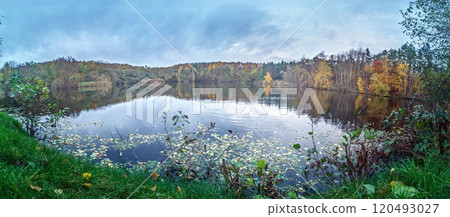 Panoramic view of a serene lake surrounded by a colorful autumn forest with vibrant foliage and reflections Panoramic view of a serene lake surrounded by a colorful autumn forest with vibrant foliage and reflections 120493027