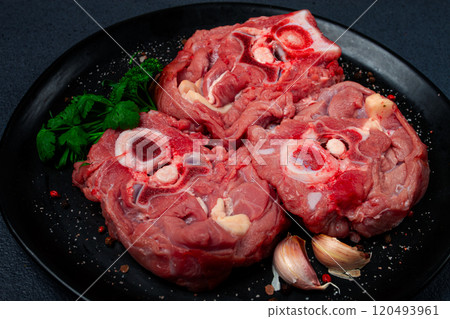 raw steak, calf's neck on the bone, fresh meat, on a black plate, top view, no people, 120493961