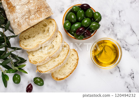 appetizer, sliced ciabatta bread, with olive oil, green olives, Chalkidiki olives, classic Green green olive, on a marble table, top view, no people, appetizer, sliced ciabatta bread, with olive oil, green olives, Chalkidiki olives, classic Green green olive, on a marble table, top view, no people, 120494232