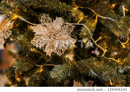Decorated Christmas tree featuring golden floral ornaments, warm glowing lights. Abstract festive background for design 120494244