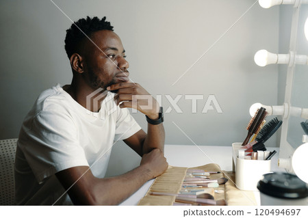 Contemplating Man in Makeup Room with Vanity Lights 120494697