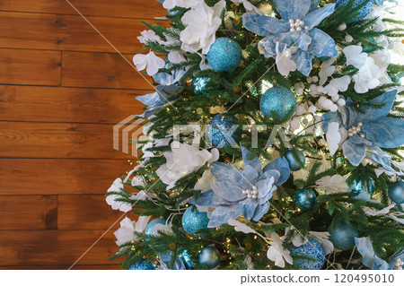 Christmas tree decorated with blue and white floral ornaments with lights and frosted snowy branches Christmas tree decorated with blue and white floral ornaments with lights and frosted snowy branches 120495010