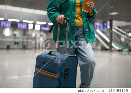 Traveler tourist happy smiling joyful fun mature elderly senior lady woman 55 years old with hand luggage, backpack holds passport and waits for flight travel at international airport terminal.  120495129