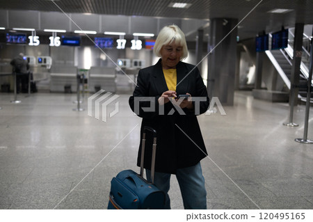 Travel Caucasian senior 60s woman traveler text messaging on cell phone at the airport, waiting for departure at the airport on vacation holiday. Travel Caucasian senior 60s woman traveler text messaging on cell phone at the airport, waiting for departure at the airport on vacation holiday. 120495165