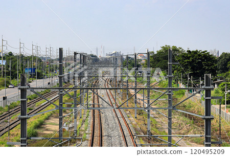 Aerial view of Infrastructure of railway tracks equipped with overhead electric poles in parallel to high powered supply lines in suburban. 120495209