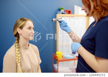 A woman at an appointment with a neurologist. A doctor examining young female patient reflexes using neurological hammer. A woman at an appointment with a neurologist. A doctor examining young female patient reflexes using neurological hammer. 120495251