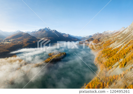 Drone view of a mountain valley with fog. Engadin valley, Switzerland. Drone view of a mountain valley with fog. Engadin valley, Switzerland. 120495261
