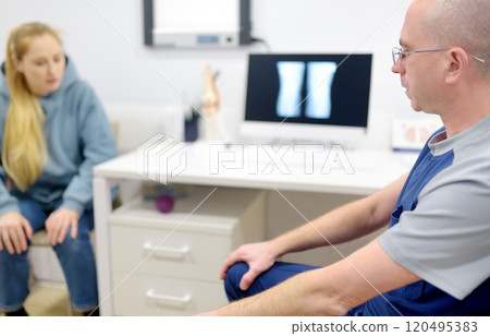 Orthopedist with female patient are during appointment in modern clinic. Doctor tells about problems of treating rheumatological disease. Orthopedist with female patient are during appointment in modern clinic. Doctor tells about problems of treating rheumatological disease. 120495383
