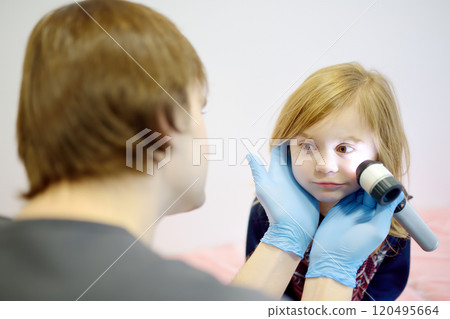 Cute little girl during appointment of dermatologist in modern clinic. Male doctor looking a pimple on a face of child. Treatment of herpes virus, streptococcus infection 120495664