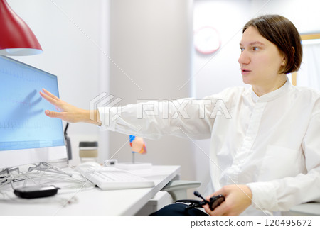 A cardiologist during appointment of patient. Doctor shows EKG on the screen of computer and explains about deviations of heart work. Cardiology consultation and treatment 120495672