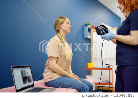 Woman with vertigo symptoms is on appointment of neurologist. Doctor making positional testing of patient with using VNG for performing Epley maneuver Woman with vertigo symptoms is on appointment of neurologist. Doctor making positional testing of patient with using VNG for performing Epley maneuver 120495885
