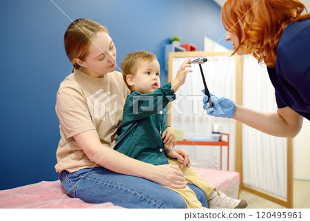 Baby and his mother are being seen by a pediatric neurologist in a modern medical clinic. Doctor conducts tests, checks the reflexes using neurological hammer of small patient. Highly qualified cure Baby and his mother are being seen by a pediatric neurologist in a modern medical clinic. Doctor conducts tests, checks the reflexes using neurological hammer of small patient. Highly qualified cure 120495961