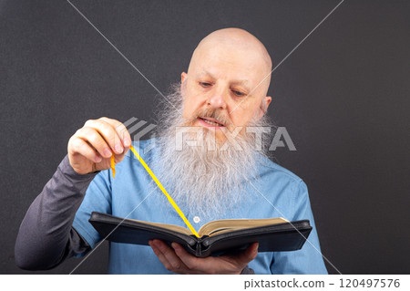 elderly christian man with a long gray beard deeply reading the bible with focused elderly christian man with a long gray beard deeply reading the bible with focused 120497576