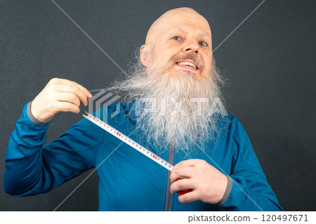 happy bald man demonstrating the length of his large white beard using a metric tape  120497671