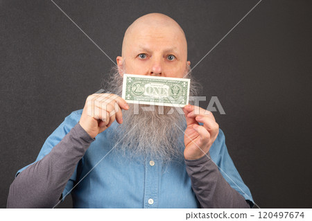 bald man with a large white beard holds a dollar in his hands. financial economics concept. 120497674