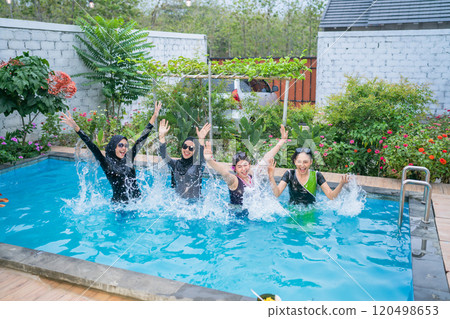 Joyful women are seen splashing around in the pool during a funfilled summer day 120498653