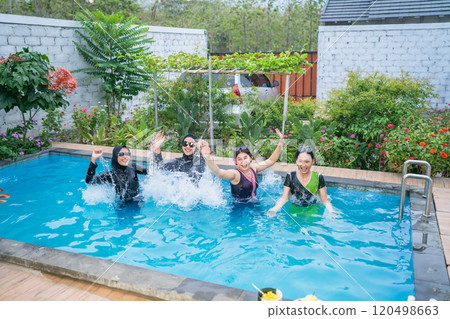 A group of joyful women are happily splashing in a beautiful pool at a tropical oasis 120498663