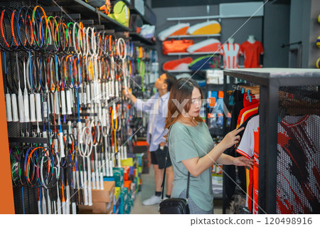 female customer choosing sport jersey before buying 120498916