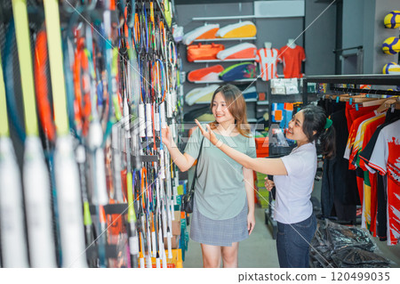 sports store saleswoman showing display badminton racket 120499035