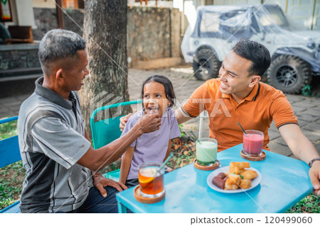 little girl fed by grandfather at lunch little girl fed by grandfather at lunch 120499060