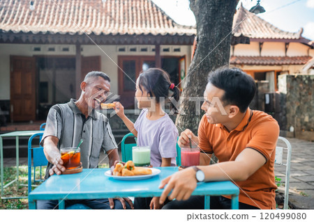 granddaughter feeding her grandfather when eating restaurant 120499080