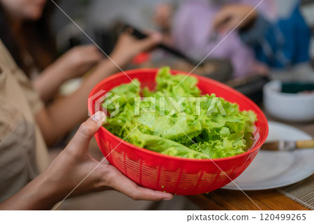 A Fresh and Colorful Green Salad Served in a Vibrant Red Bowl at a Social Gathering Event 120499265