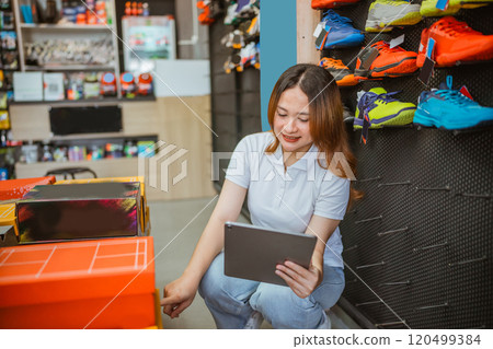 athletic shoes store saleswoman checking inventory using tablet athletic shoes store saleswoman checking inventory using tablet 120499384