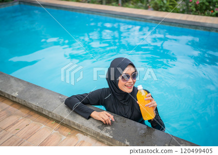 Enjoying Refreshing Moments of Poolside Relaxation with a Drink in a Tropical Setting 120499405